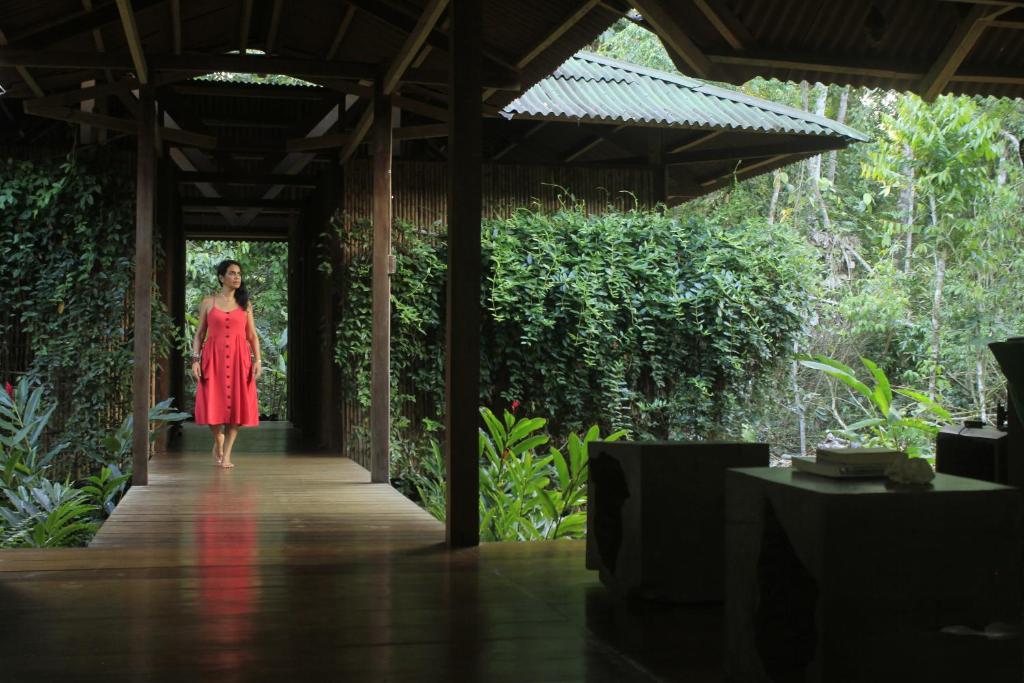 Una donna con un vestito rosso che cammina lungo un vialetto di legno di Casa Amazonas a Puerto Maldonado