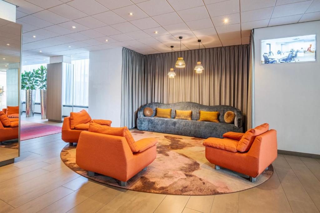 salon z pomarańczowymi krzesłami i kanapą w obiekcie Crowne Plaza Antwerpen, an IHG Hotel w Antwerpii