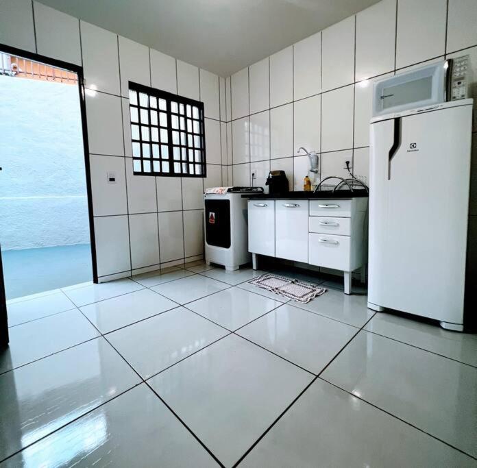 cocina con electrodomésticos blancos y nevera blanca en Casa privativa próximo ao centro e aeroporto. en Campo Grande