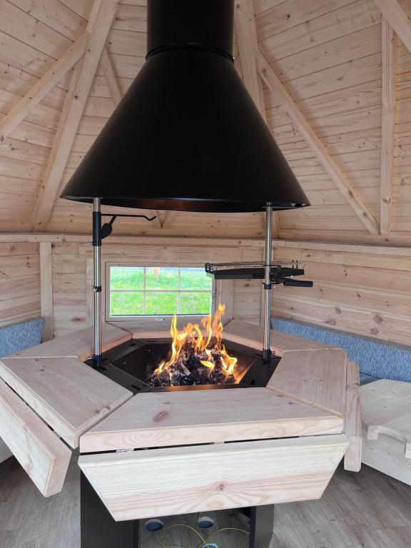 una chimenea en una cabaña de madera con techo negro en Capledrae Farmstay Shepherds Huts, en Cardenden