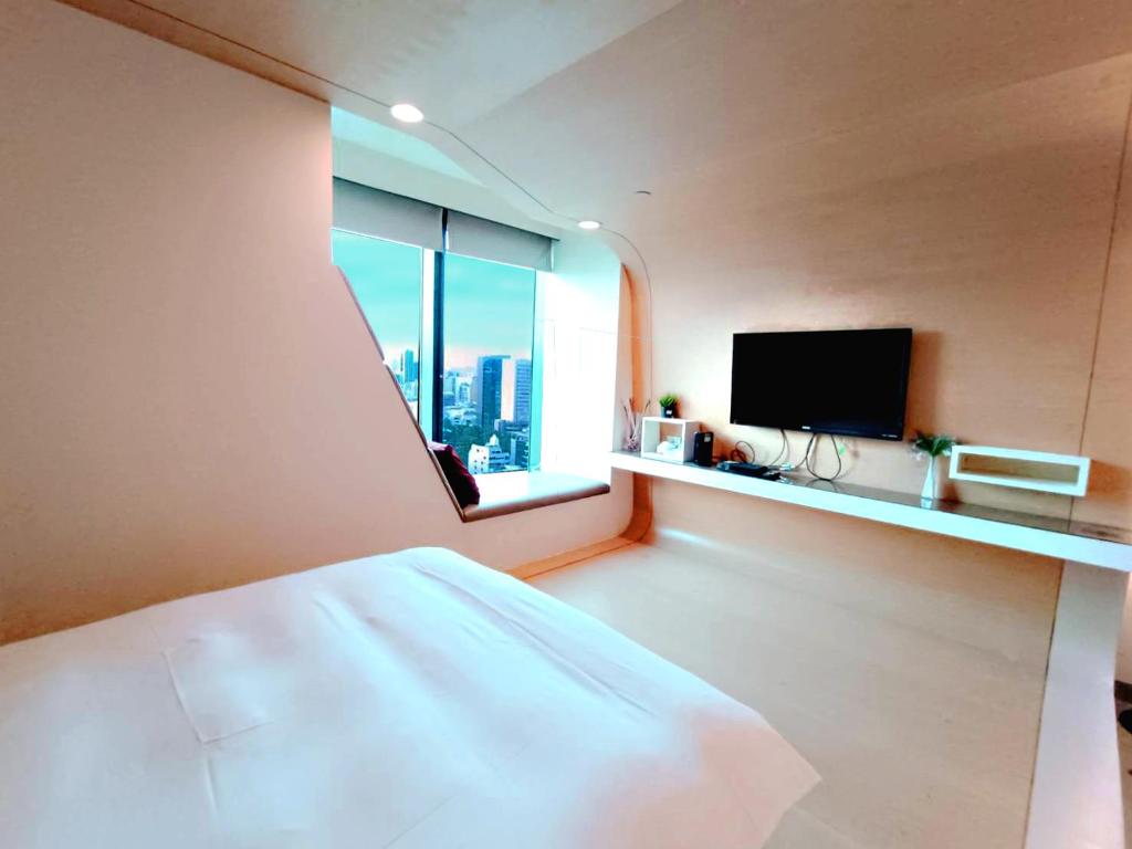 1 dormitorio con 1 cama y ventana con TV en 三条文旅, en Kaohsiung