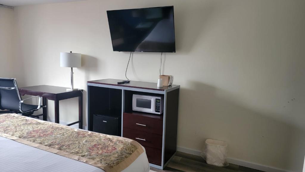 a hotel room with a bed and a microwave on a cabinet at Town Inn in Bordentown