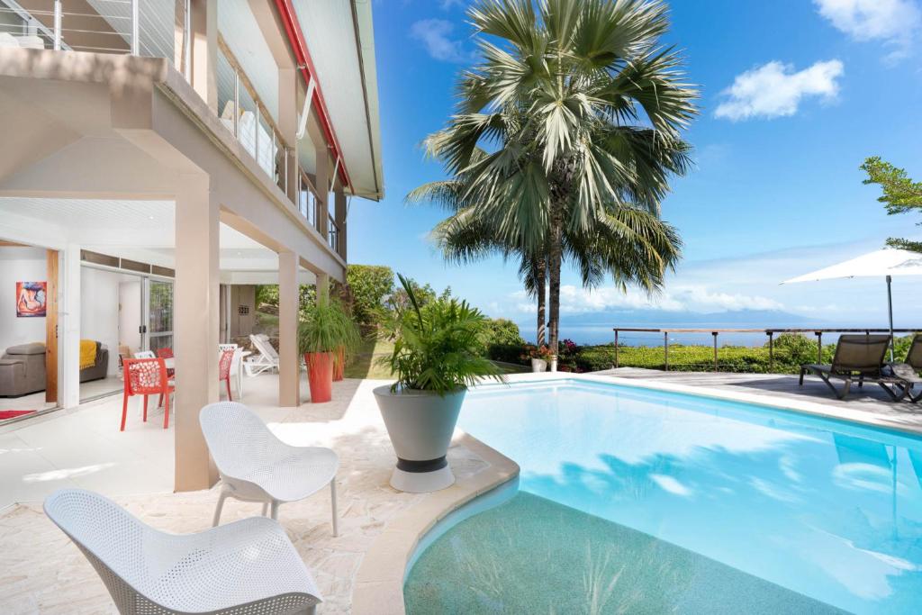 a villa with a swimming pool and a palm tree at Villa Lodge - Bas de Villa avec piscine et vue océan et Moorea in Punaauia