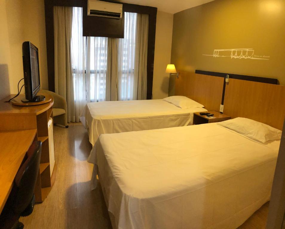 a hotel room with two beds and a flat screen tv at Flat 609 - Comfort Hotel Taguatinga in Brasília
