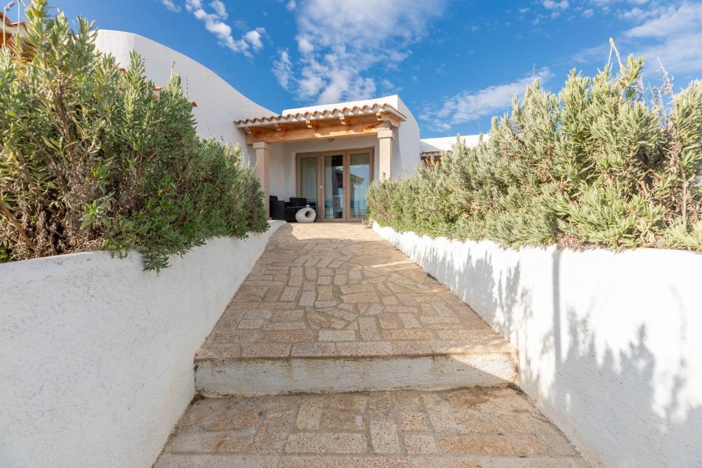a pathway leading to a white house with bushes at Sea View House 5 in Olbia