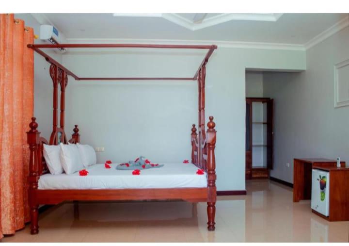 a bedroom with a canopy bed with red flowers on it at Taj hotel partnership in Nungwi