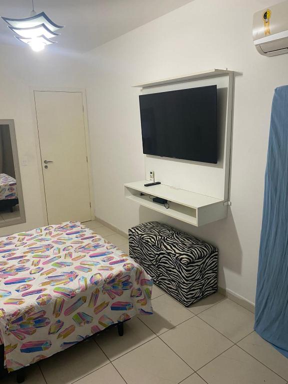 een slaapkamer met een bed en een flatscreen-tv bij AP do JP in Praia Grande