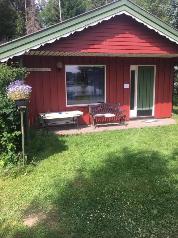 a red shed with a picnic table and a bench at Rønlund Hyttepark, Midt-i-garde in Ron