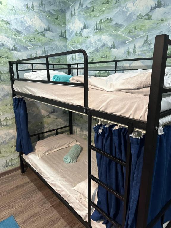 Ce lit superposé se trouve dans un dortoir orné d'une fresque murale de montagne. dans l'établissement Ultra Hostel, à Douchanbé