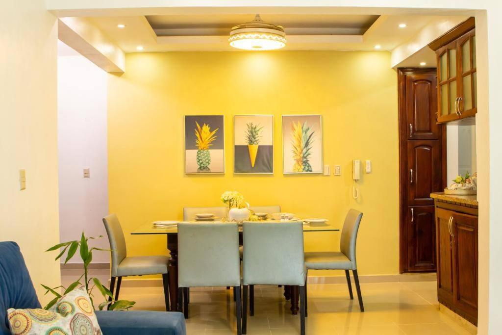 Confortable apartamento- Cotuí في Cotuí: غرفة طعام صفراء مع طاولة وكراسي