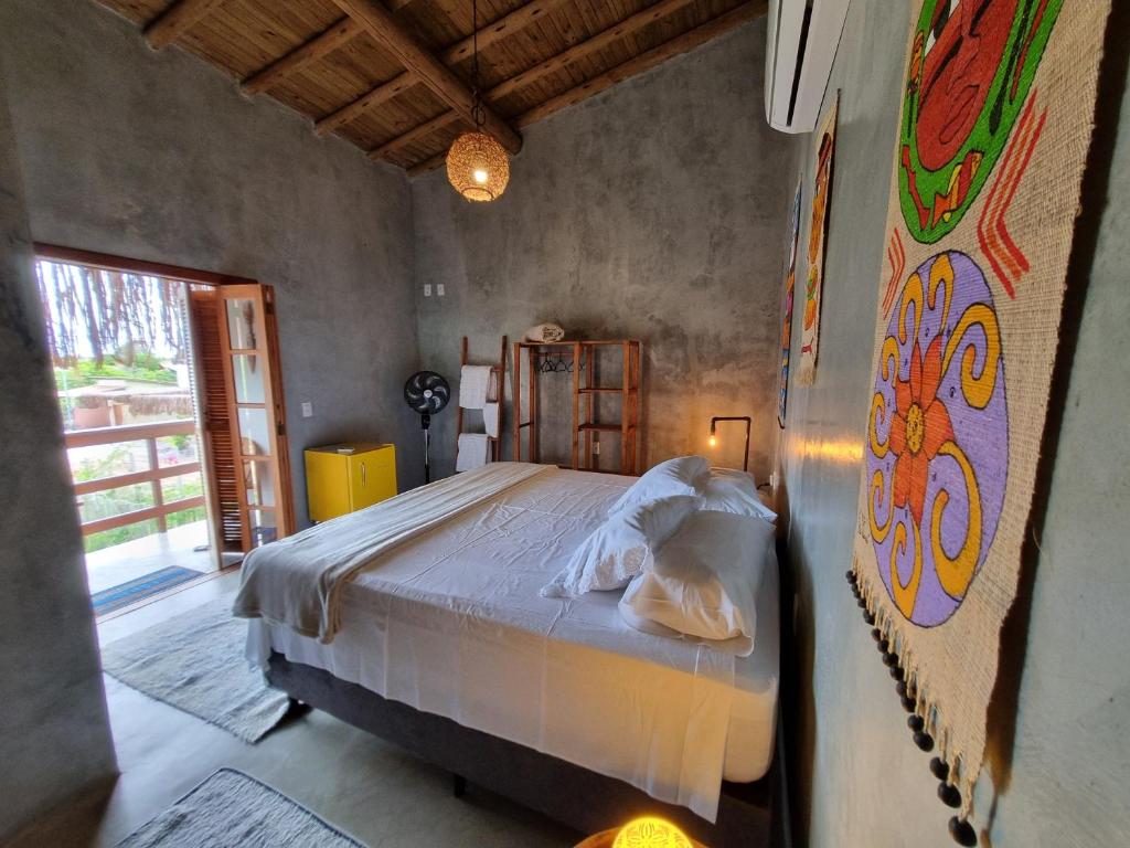 een slaapkamer met een bed en een schilderij aan de muur bij Pousada TAUANE in Caraíva