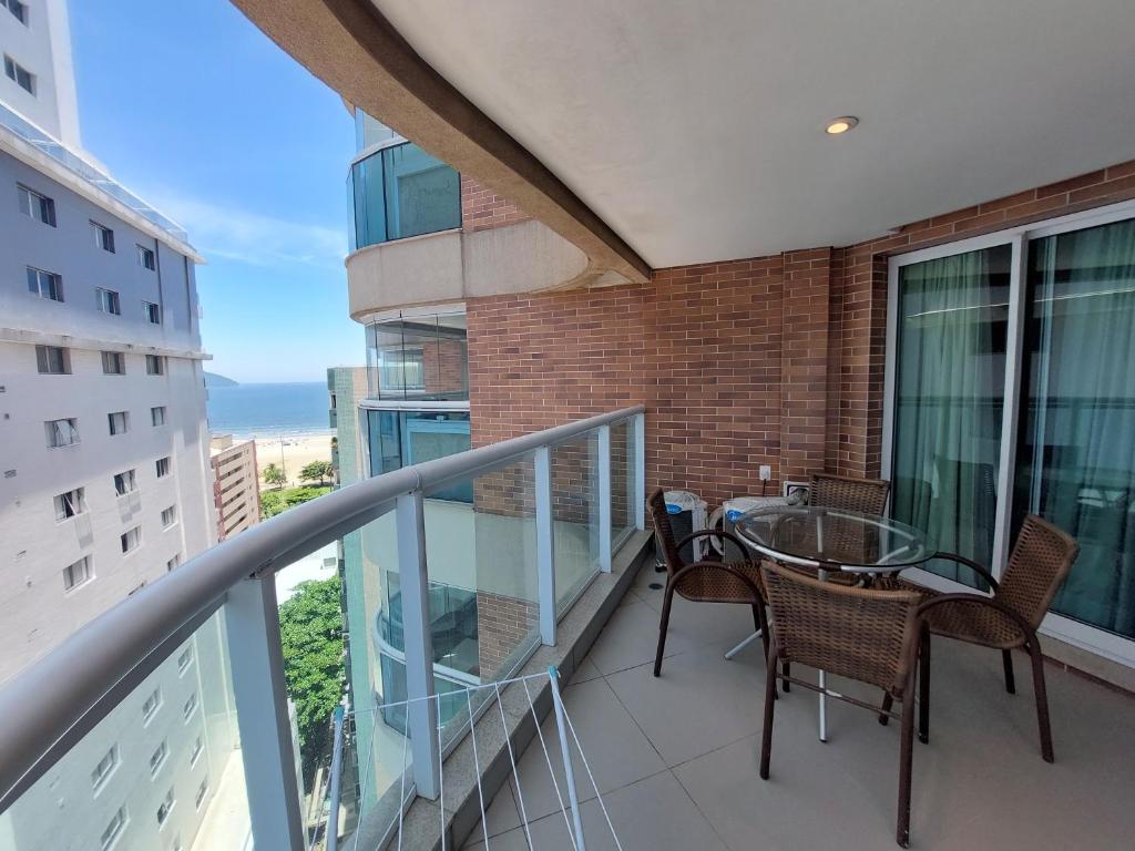 a balcony with a glass table and chairs on a building at BookSantos Estanconfor 1503 -Charmoso e Próximo à Praia! in Santos