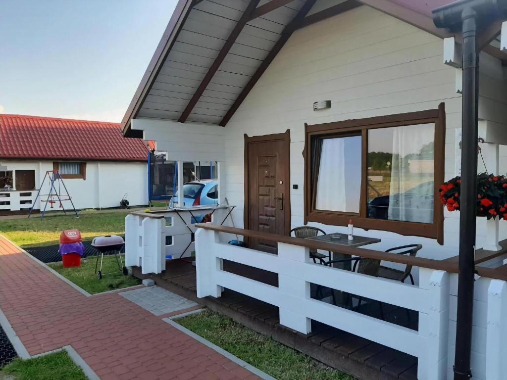 a white house with a fence and a table at Comfortable 4-person cottages, Ustronie Morskie in Ustronie Morskie