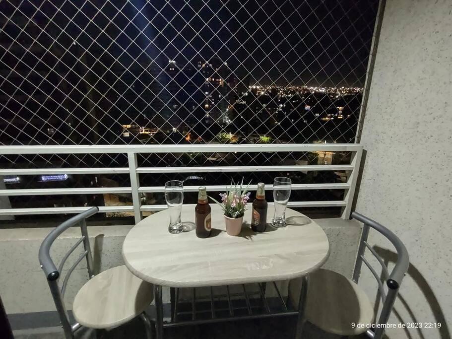 Apartamento La Florida Mirador في سانتياغو: طاولة مع كؤوس النبيذ والزهور على الشرفة