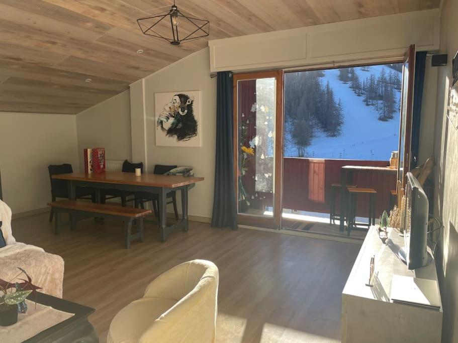 a living room with a table and a view of a mountain at Valberg 3 pièces au pied des pistes in Péone