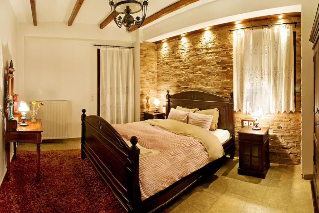 1 dormitorio con 1 cama grande y pared de ladrillo en Αρχοντικό Ειρήνη - 6 Metsovo, en Metsovo