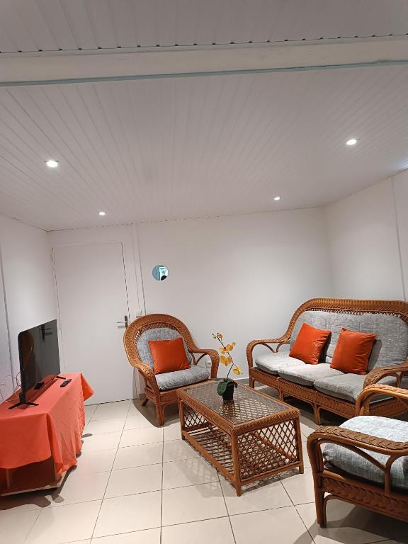 a living room with wicker furniture and a tv at Chez Clo in Le Gosier