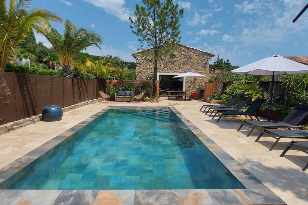 einen Pool im Hinterhof mit Stühlen und Sonnenschirmen in der Unterkunft Villa avec piscine proche mer et saint tropez in Grimaud