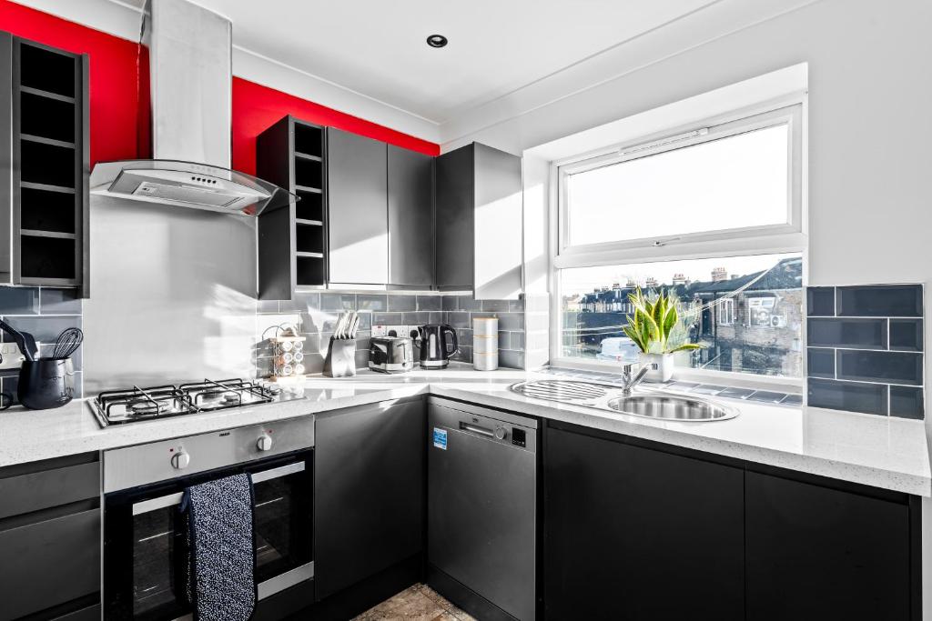 a kitchen with black and white appliances and a window at Cosy 2 Bedroom Flat in East Ham, Close to Excel in London
