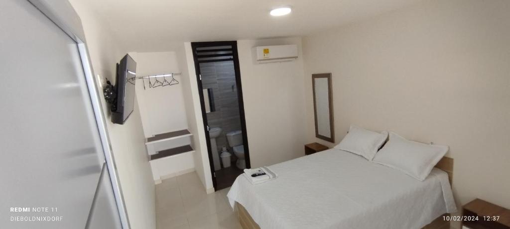 a small bedroom with a white bed and a window at Habitaciones Cataleya Valledupar in Valledupar