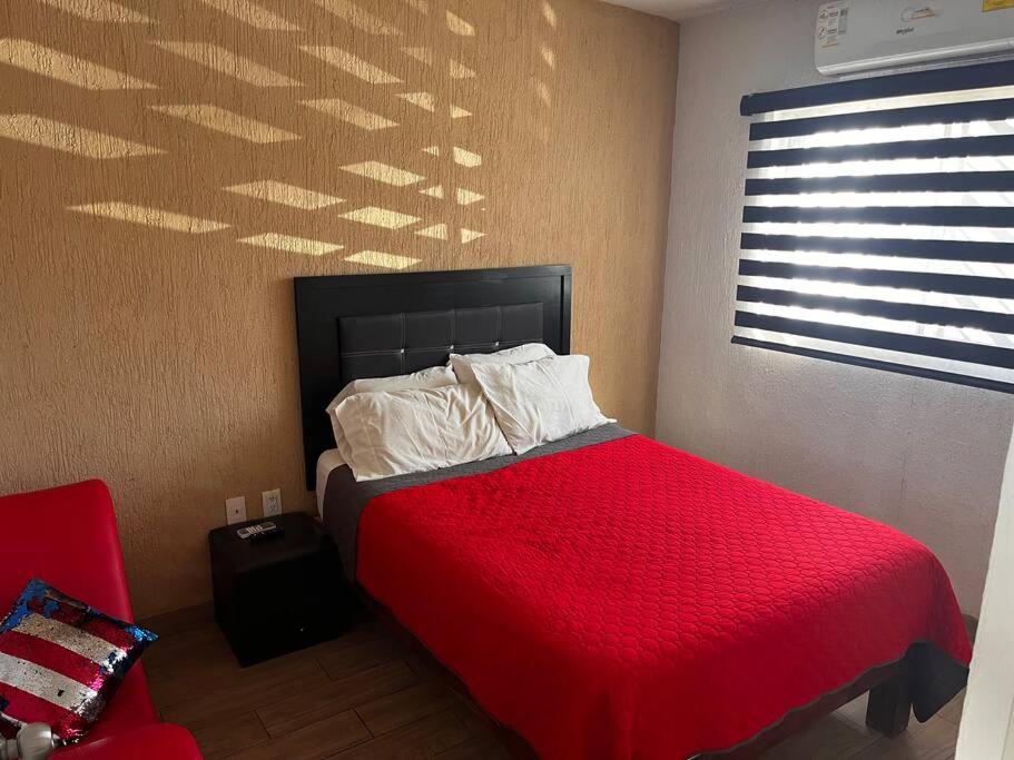 1 dormitorio con cama roja y silla roja en Residencia en Ciudad Guzmán, en Ciudad Guzmán