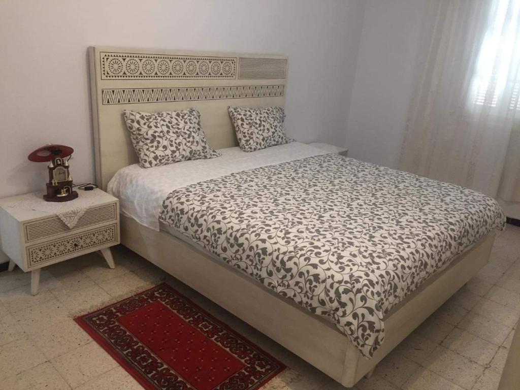 een slaapkamer met een bed en een nachtkastje met een bed sidx sidx bij Home2Home in Nabeul