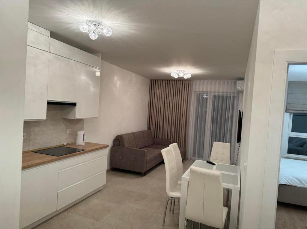 a kitchen and living room with a table and a couch at Apartament JANICKIEGO 159 parking free in Poznań