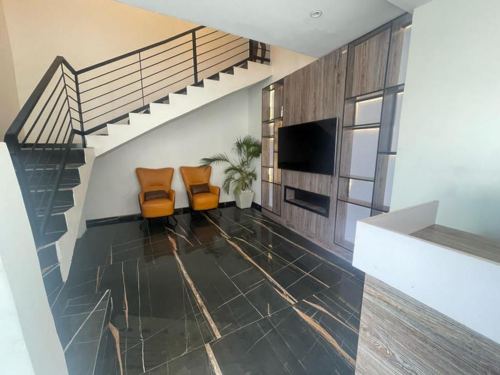 a living room with two chairs and a staircase at The Zodiac House. in Lekki