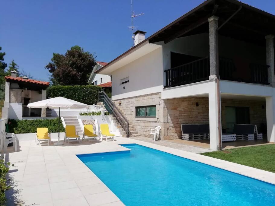 a villa with a swimming pool in front of a house at Casa da Encosta Chaves in Chaves