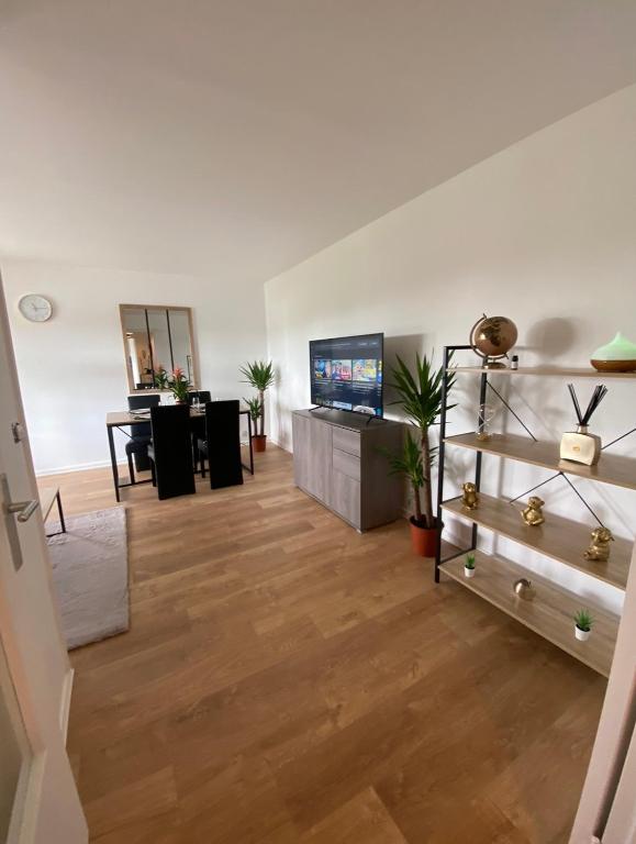 a living room with wooden floors and a tv at Appartement 59m2 professionnel ou familial Saint Quentin en Yvelines in Montigny-le-Bretonneux