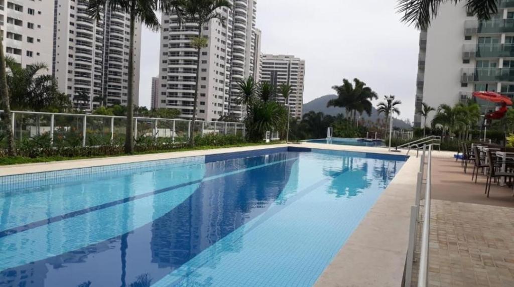 a large swimming pool in a city with tall buildings at Loft Ilha Pura in Rio de Janeiro