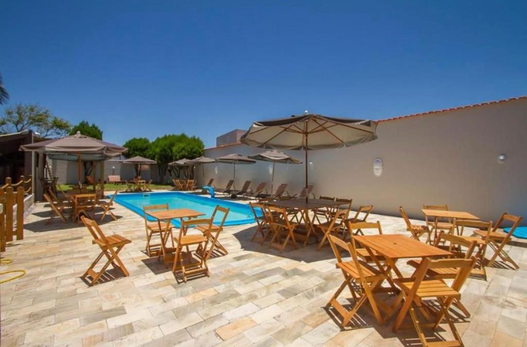 a patio with tables and chairs and a swimming pool at Hostel Costa Terral in Matinhos