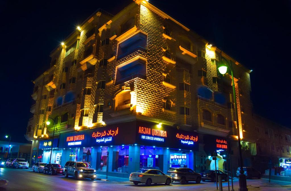 um edifício com carros estacionados numa rua à noite em ارجان قرطبة للشقق المخدومة em Al Khobar