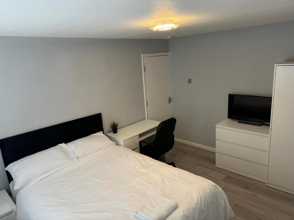 Schlafzimmer mit einem Bett, einem Schreibtisch und einem TV in der Unterkunft Divine touch in Plumstead