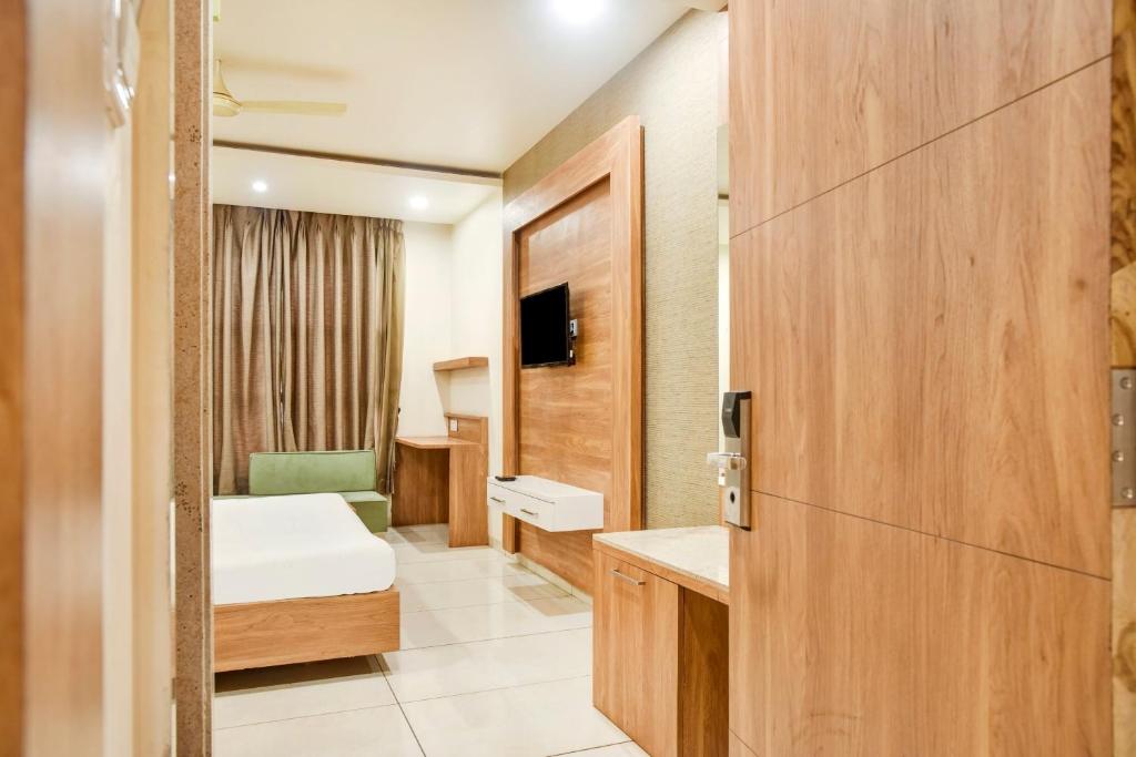 a small room with a bed and a door at Capital O 82561 Hotel Om Palace in Bhopal