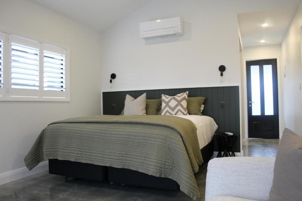 a bedroom with a large bed with a green blanket at Ahuru House in Mangawhai