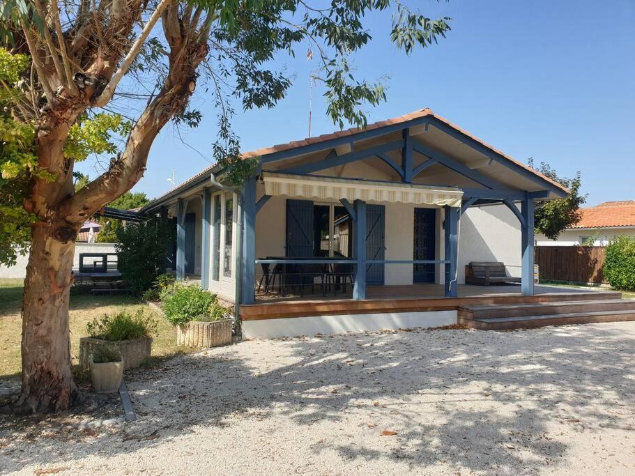 uma pequena casa com um alpendre e uma árvore em Maison chaleureuse 3* à deux pas de la plage em Gujan-Mestras