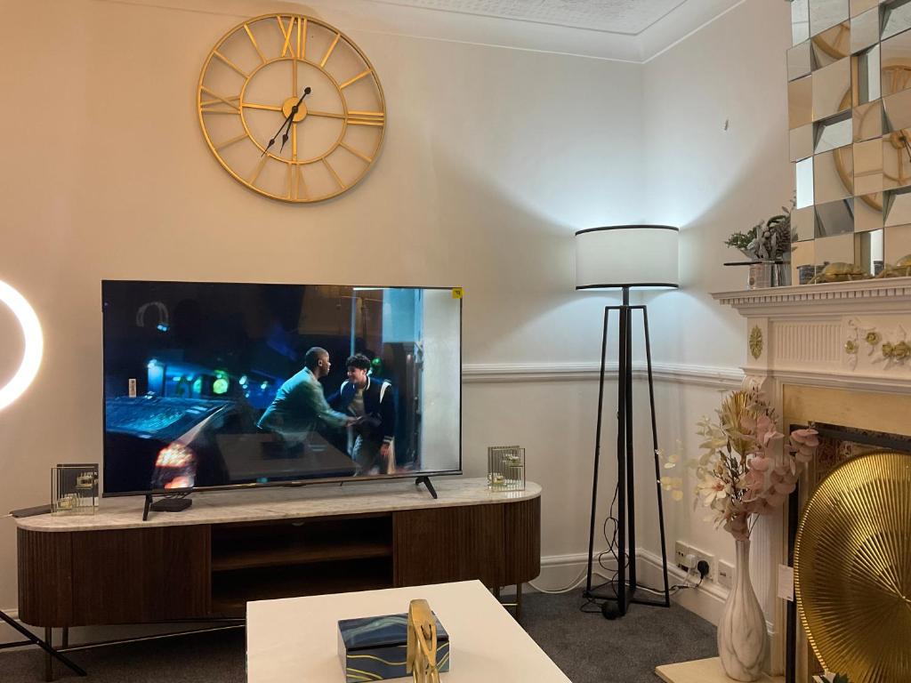 a living room with a large tv and a clock at MAYE HOUSE 