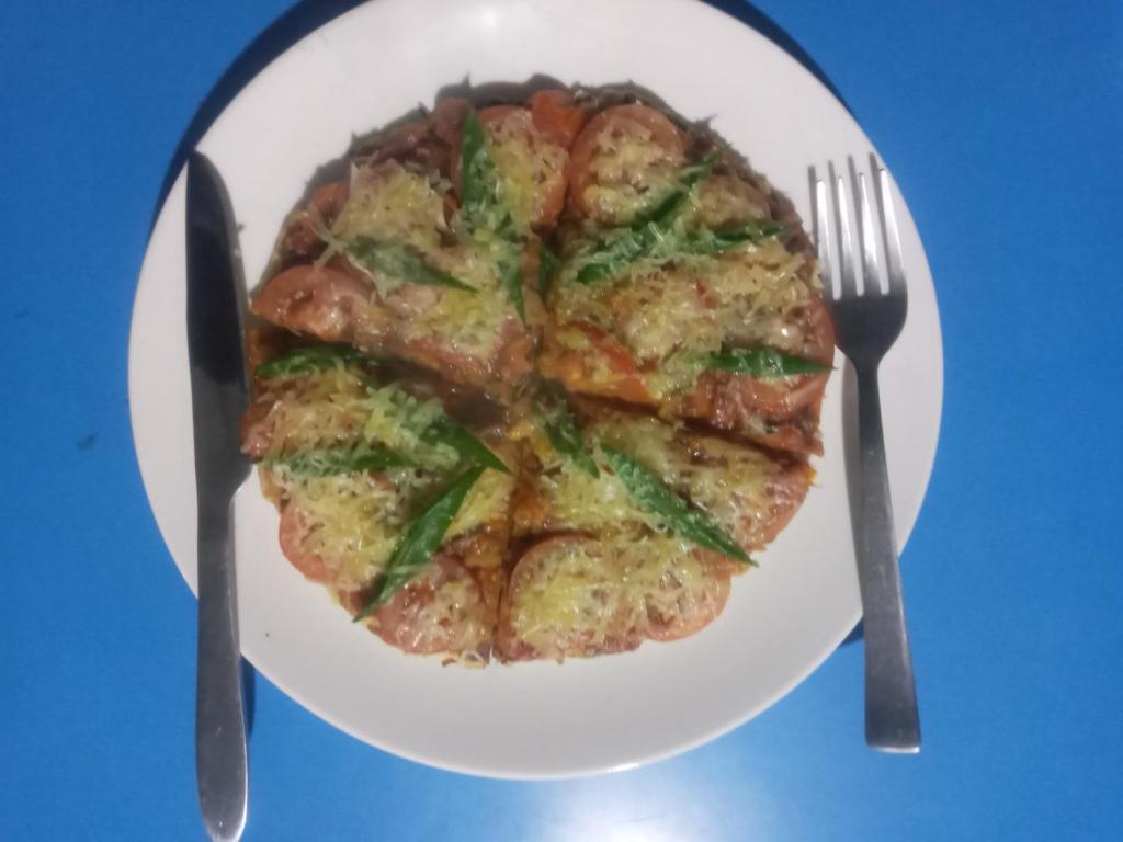a plate of food with a pizza and a fork and knife at Unique point home stay in Nagarkot