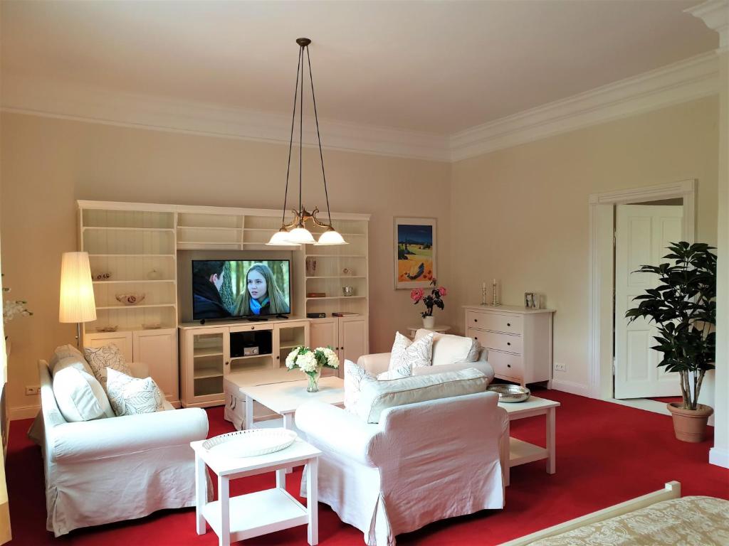 een woonkamer met witte meubels en een televisie bij fewo1846 - Suite Royal Museumsberg in Flensburg