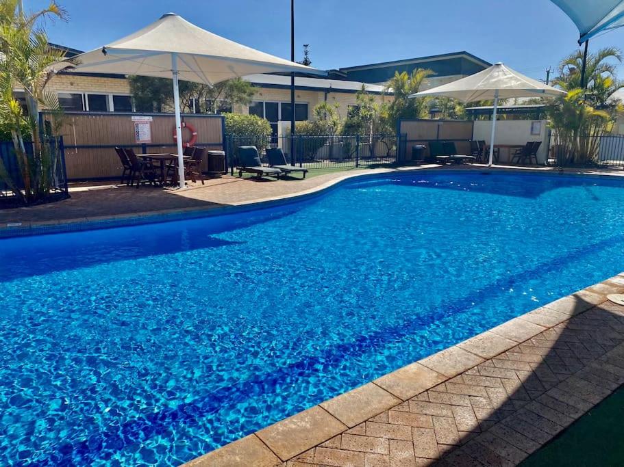 a large blue swimming pool with an umbrella at Mariner Resort Comfort - unit 165 in Geraldton