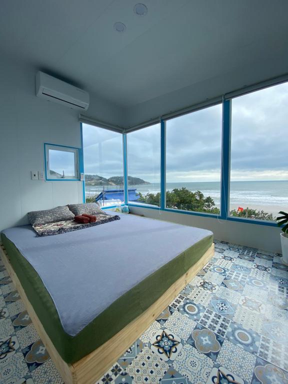 a bedroom with a large bed and large windows at nhà Ba cơm Má in Phương Phi