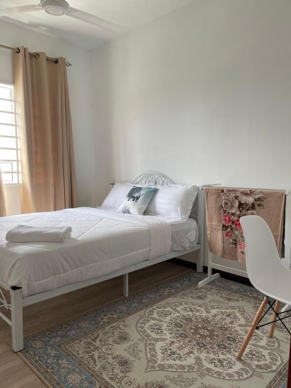 ein weißes Schlafzimmer mit einem Bett und einem Stuhl in der Unterkunft Aida Homestay in Kuala Terengganu