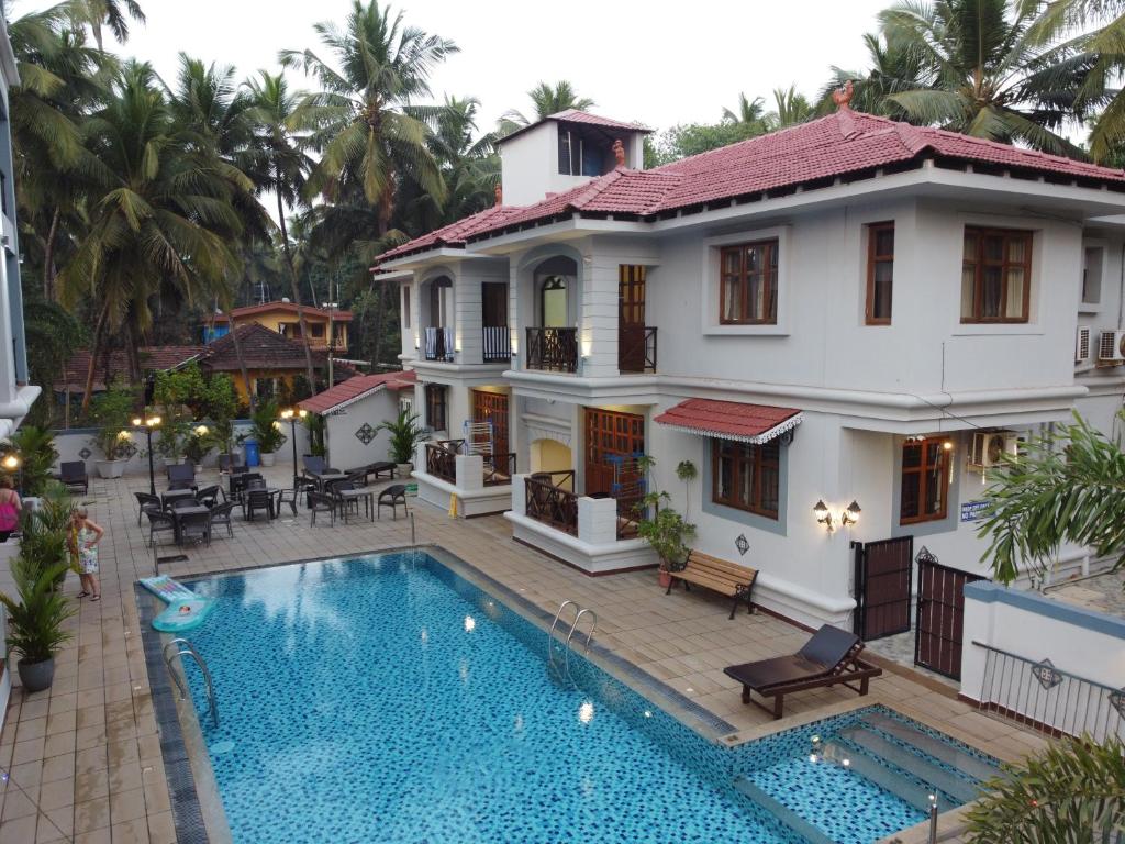a villa with a swimming pool in front of a house at Coastal Suites Apartment Hotel ---- 8 minutes walk to beach in Benaulim