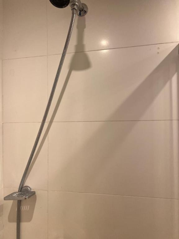a shower head in a bathroom with white tiles at Flat confortável e econômico hotel condomínio cristal place in Goiânia