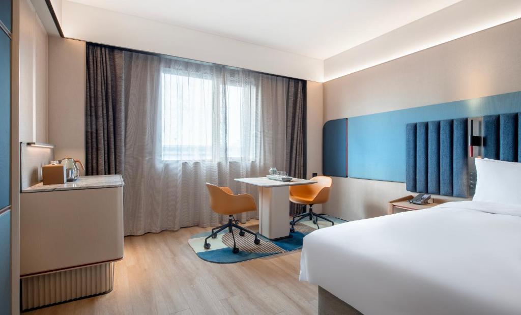 a hotel room with a bed and a table and chairs at IntercityHotel Shanghai Hongqiao Airport - Free Minibar for First Night in Shanghai
