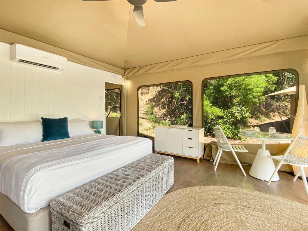 1 dormitorio con 1 cama, mesa y sillas en Magnetic Glamping Tent 3 en Nelly Bay