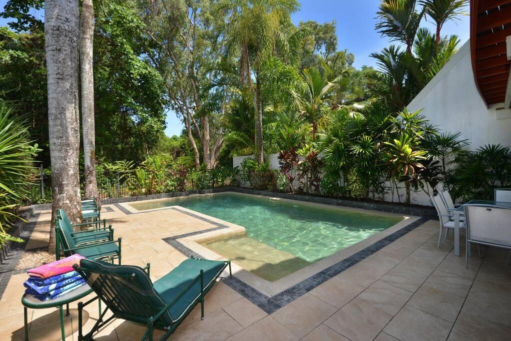 a swimming pool with two lawn chairs and a table at The Condo - A Spacious Villa Near Beach and Town in Port Douglas