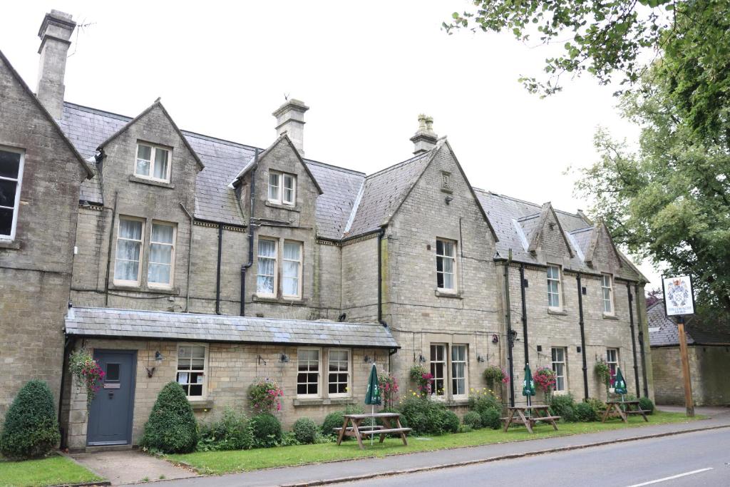 an old stone building with benches in front of it at The Tollemache Arms in Buckminster