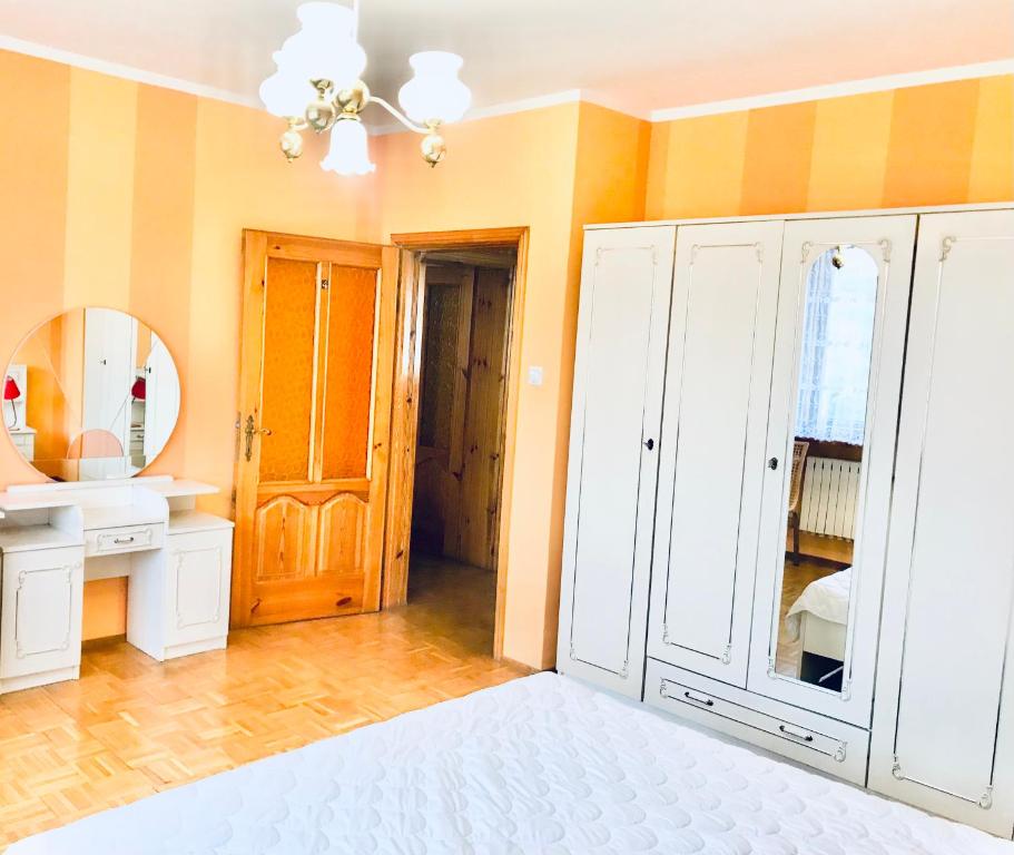 baño con armario blanco y espejo en Hostel Odlot Ławica pokoje na wyłączność, en Poznan